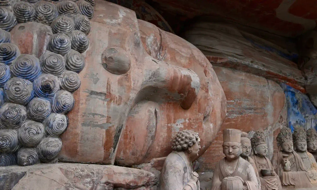 Detailed Buddhist sculptures carved into a sandstone cliff at Dazu Rock Carvings, a historic cultural attraction near Chongqing, China.